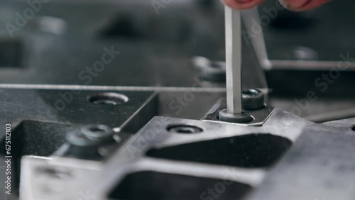 Close up of a hex key screwing in a bolt on a big metal components in the factory photo