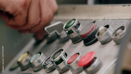 A factory worker operating knobs and dials on a metal grinding machine photo