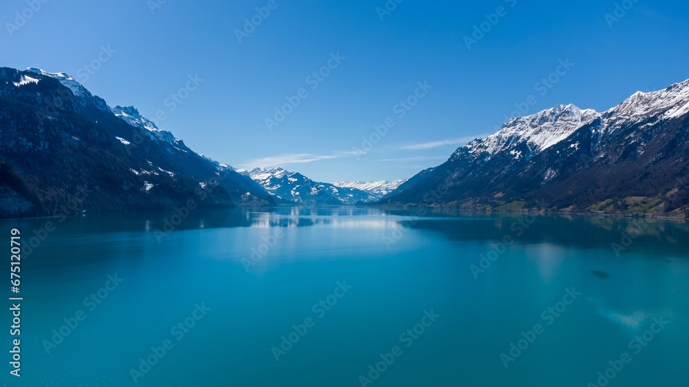 Landscape of a lake surrounded by rocky hills covered in the snow in Brienz, Switzerl