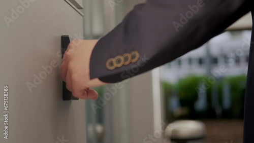 Man in suit opens the door to office building, using a NFC key card, photo