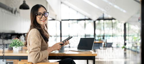 Smiling businesswoman using her phone in the office. Small business entrepreneur sitting at office and looking at camera photo