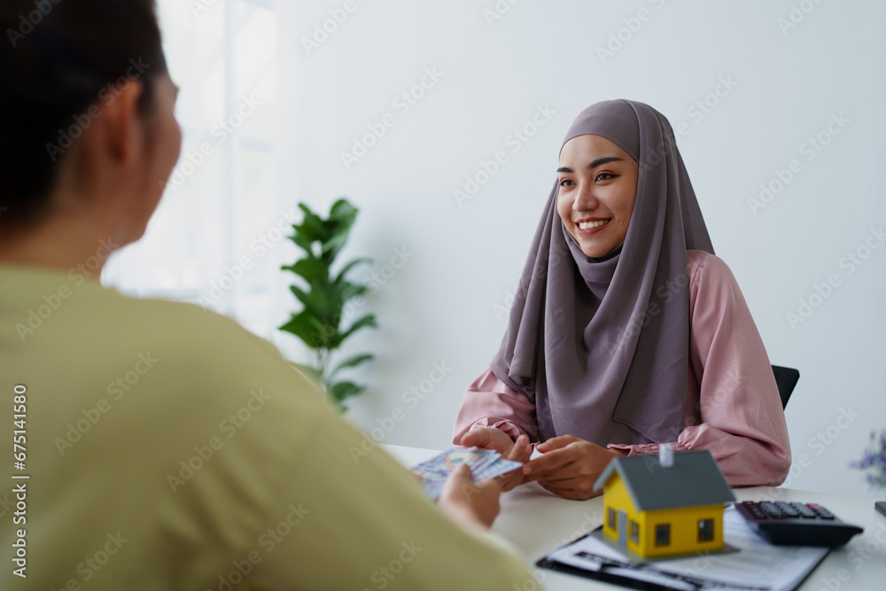 A female Muslim bank employee, making an agreement on a residential loan with a customer. A female Muslim bank employee, making an agreement on a residential loan with a customer.