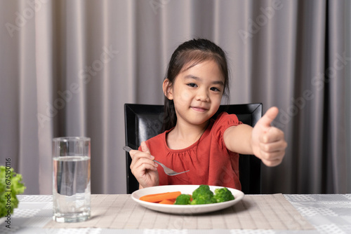 Cute little girl showing thumb showing eating healthy vegetables.
