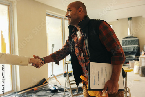 Professional contractor shakes hands with happy homeowner for interior renovation project photo