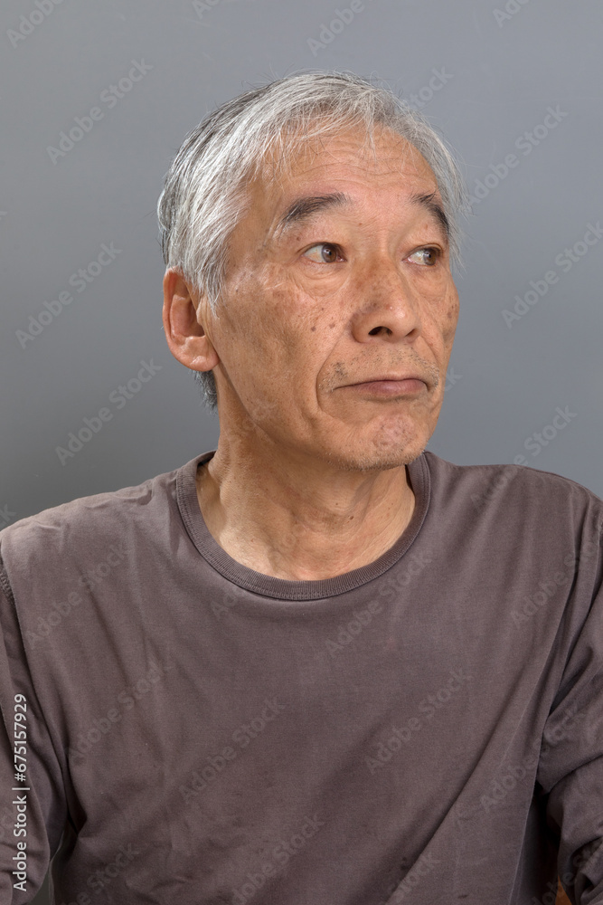 白髪混じりの60代の男性が、横を向き何かに気を取られている 白髪混じりの60代の男性が、横を向き何かに気を取られている