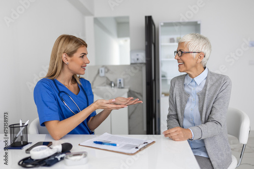 Young woman doctor or GP in white medical uniform consult female patient in private hospital. Female therapist speak talk with senior woman client on consultation in clinic. © Graphicroyalty