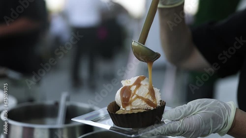Server Drizzling Hot Caramel Syrup Topping on Vanilla Ice Cream Desseert photo