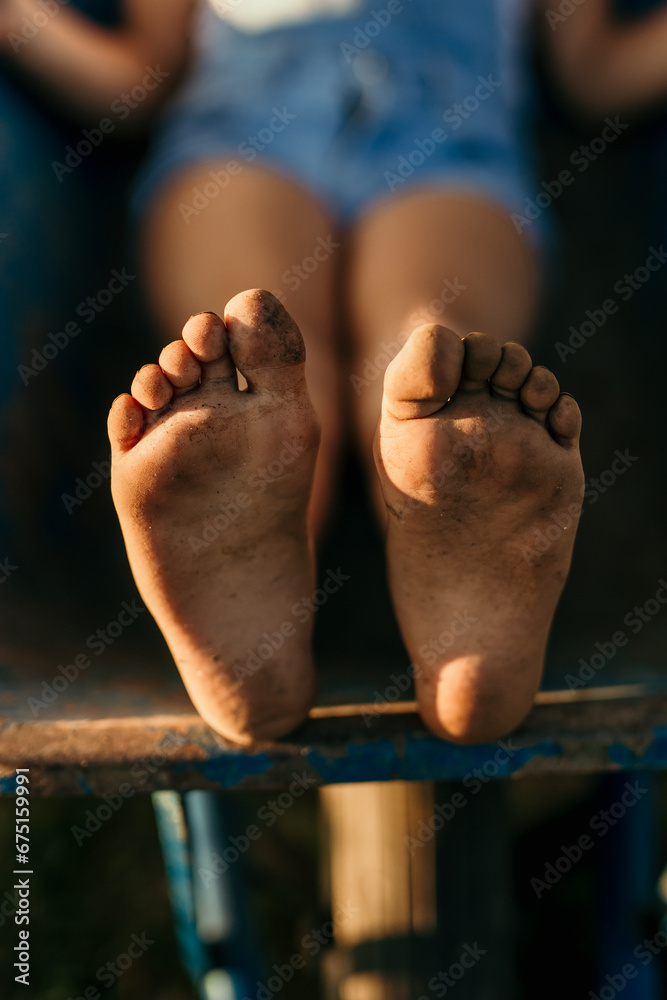 Fototapeta premium Countryside barefoot kid with dirty feet outdoors. 