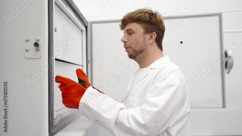 Scientist man opening big freezer to take samples away. Doctor working in laboratory
