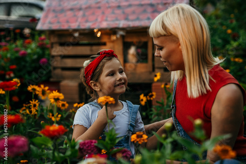 Loving mom and daughter tending a colorful countryside flower garden