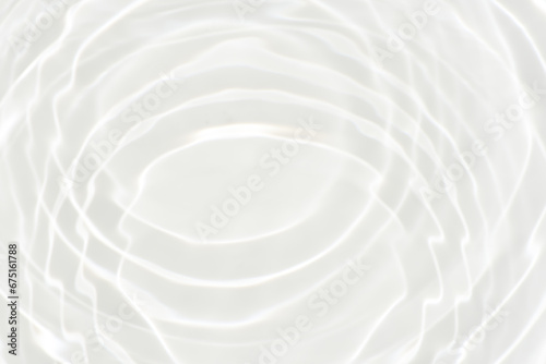 White water with ripples on the surface. Defocus blurred transparent white colored clear calm water surface texture with splashes and bubbles. Water waves with shining pattern texture background.