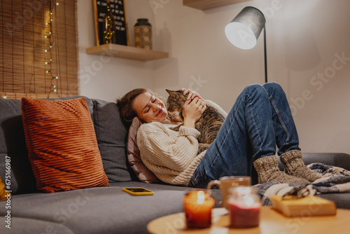 Cozy at home with tabby cat, woman with her pet on sofa ay home in evening photo