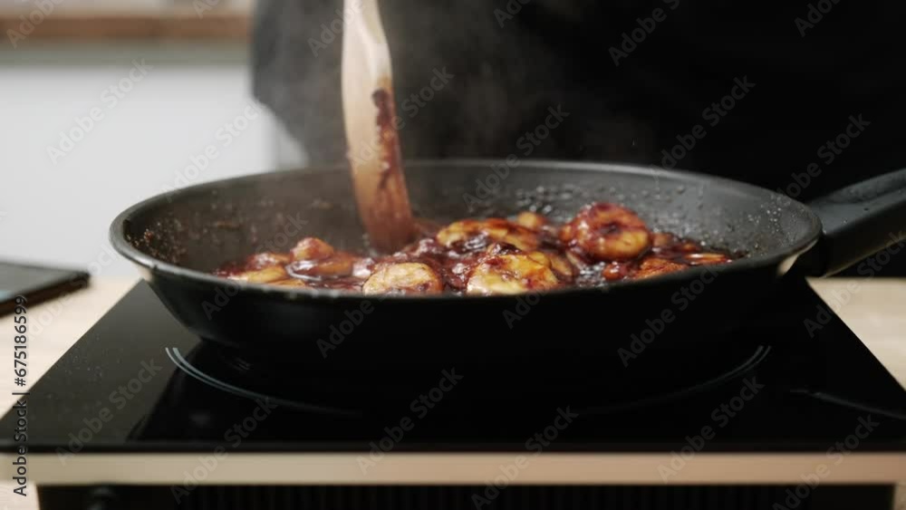 The cook caramelizes bananas in a frying pan. the cook prepares sweet dessert according to the recipe. The cook caramelizes bananas in a frying pan. the cook prepares sweet dessert according to the recipe.