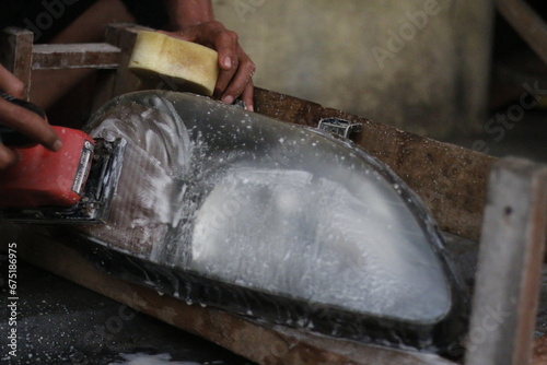 The process of rubbing very dirty car headlights using water and soap.