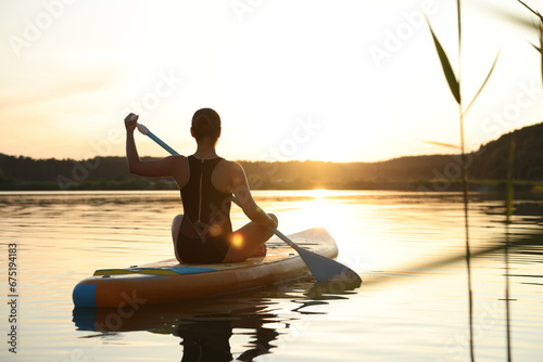 Woman paddle boarding on SUP board in river at sunset, back view © New Africa