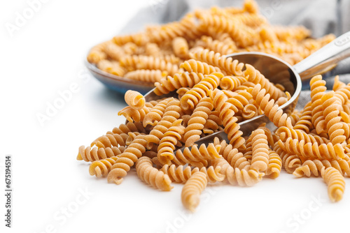 Raw whole grain fusilli pasta. Uncooked pasta in scoop isolated on white background.