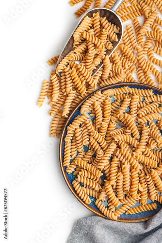 Raw whole grain fusilli pasta. Uncooked pasta on plate isolated on white background.
