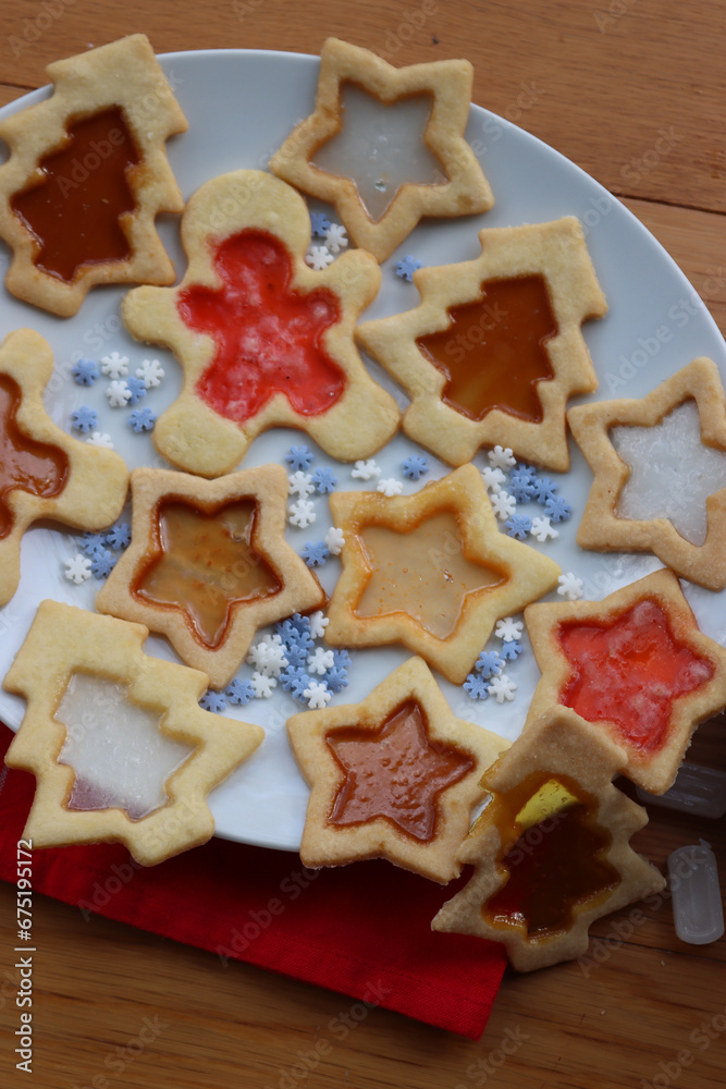 Fototapeta premium Christmas cookies with fake “glass” made of melted candies on plate on wooden table with festive decorations