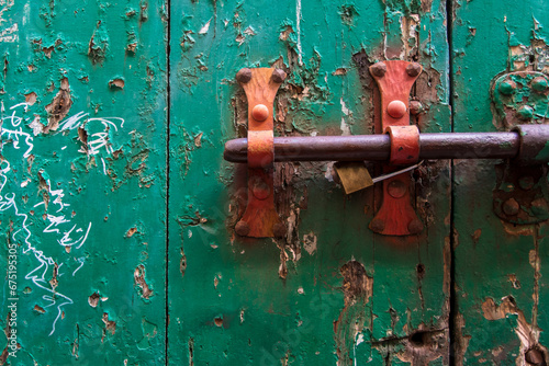 Dettaglio di un chiavistello arrugginito su una vecchia porta di legno dipinta di verde photo