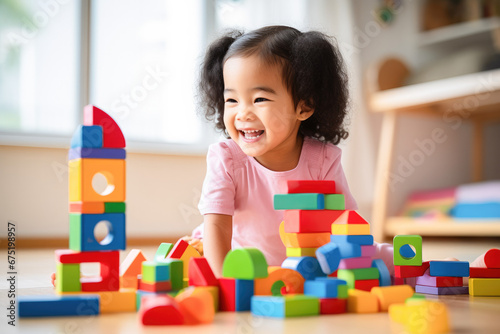 Happy cute toddler playing on floor with colorful wooden block toys. Learning by playing concept. 