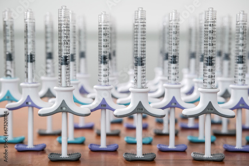 Collection of dermal tuberculin syringes in a row on wooden background. Colorful filler syringes decorating aesthetic clinic or salon. Beauty concept