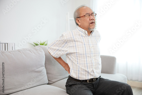 Photography senior man suffering from back pain on sofa