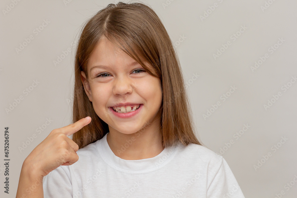 Portrait of caucasian little girl with open wide smile showing on good teeth by index finger looking at camera Portrait of caucasian little girl with open wide smile showing on good teeth by index finger looking at camera