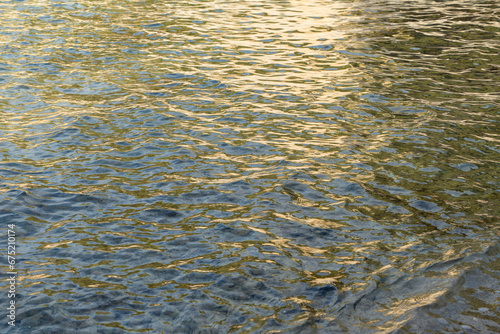 abstract reflecions of sunlight on the rippled water surface in the morning golden and gray background