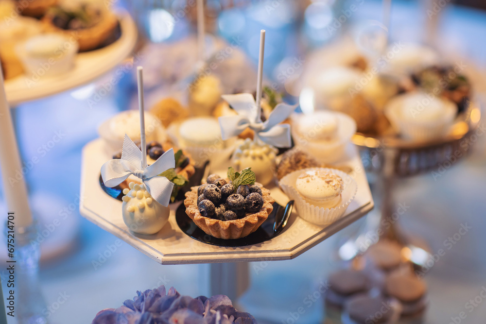 Naklejka premium Baby shower party for boy. Tasty treats on table decorated with flowers and balloons. Table with sweets on holiday. A beautiful sweet candy bar with muffins, cakes, fruits, marshmallows and flowers.