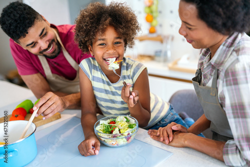 Overjoyed young african american family with kid have fun cooking at home together 