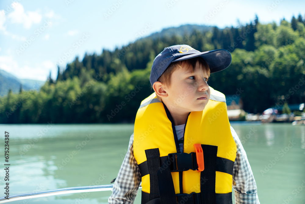 boy wearing safety vest feel sick sailing paddleboat on beautiful Lake. mountains on background