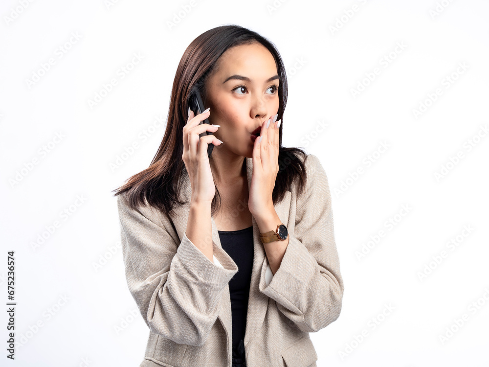 A portrait of an Indonesian Asian woman wearing a cream-colored blazer, talking on the phone. Isolated against a white background. A portrait of an Indonesian Asian woman wearing a cream-colored blazer, talking on the phone. Isolated against a white background.
