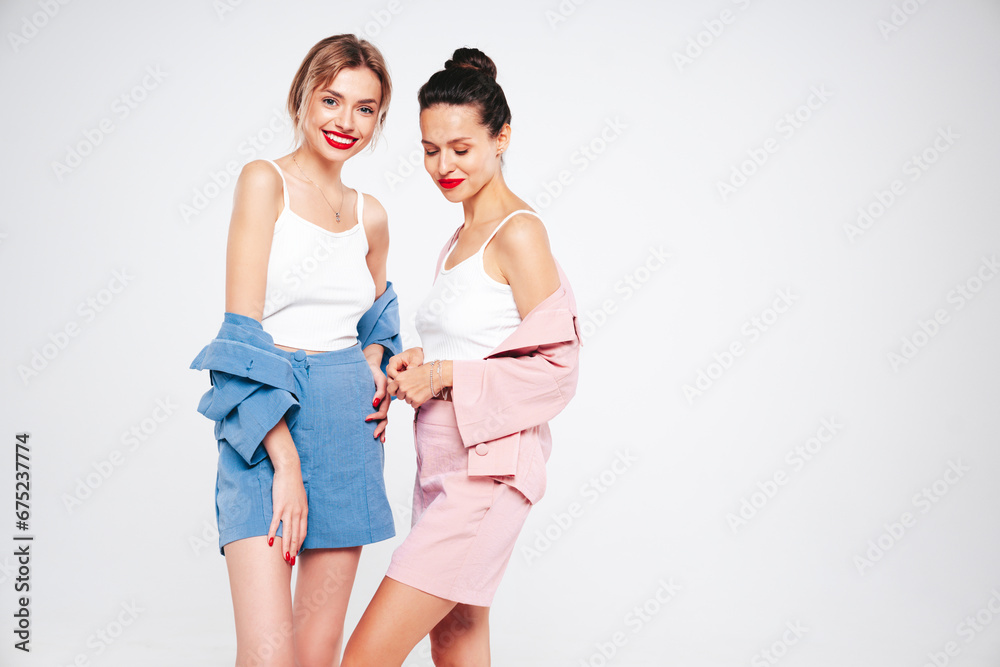 Two young beautiful smiling brunette hipster female in trendy summer clothes. Sexy carefree women posing on white background in studio. Positive models having fun. Cheerful and happy. Isolated Two young beautiful smiling brunette hipster female in trendy summer clothes. Sexy carefree women posing on white background in studio. Positive models having fun. Cheerful and happy. Isolated