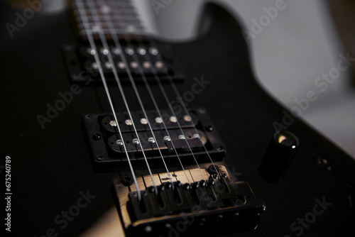 Part of a black electric guitar, strings close. Musical instruments, learning to play the guitar