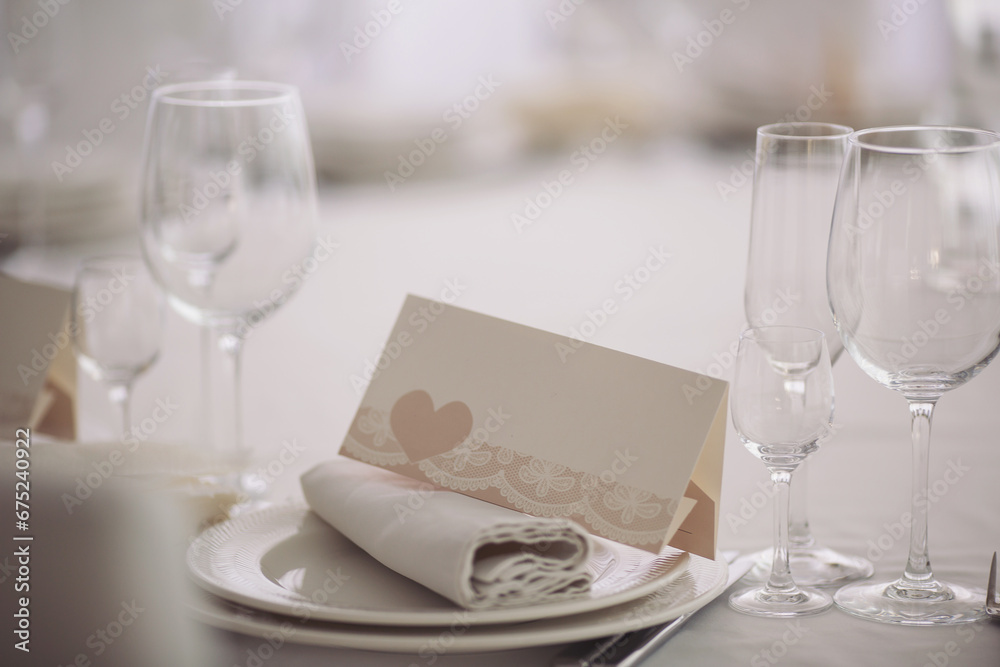 festive tables at the wedding party, on the tables are plates with napkins and cards, glasses. elegant dinner table setting in restaurant or hotel. festive tables at the wedding party, on the tables are plates with napkins and cards, glasses. elegant dinner table setting in restaurant or hotel.