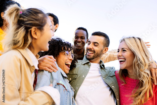 Young group of diverse college students having fun outdoors. Multiracial best millennial friends enjoying free time at city street. Youth community and friendship concept. #675241969