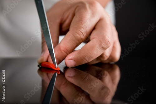 Close up of a chef hands deseeding a red bird's eye chili
 photo