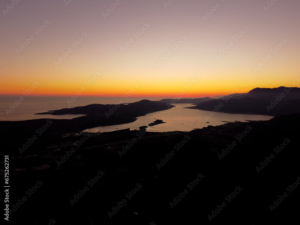 Aerial drone view of beautiful sunset or sunrise landscape with clear sky in the Bay of Kotor, Adriatic sea, Montenegro. Tranquil skyline with bright orange sunlight. Summer holiday concept