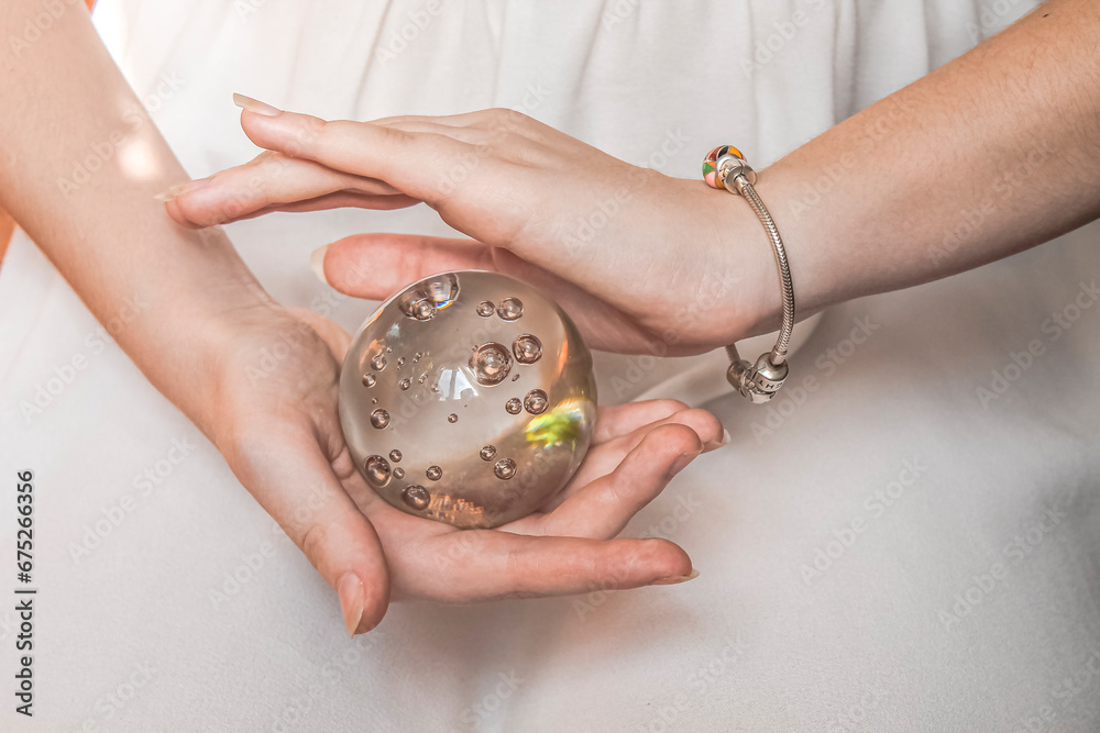 Magic glass ball in the hands of a girl on a light background Magic glass ball in the hands of a girl on a light background