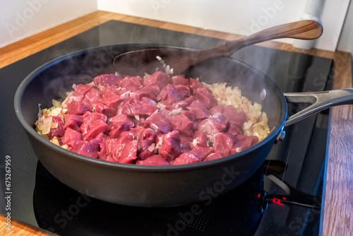 sliced onions and meat are frying in a pan