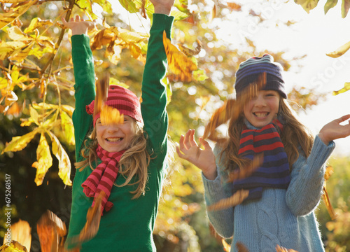 Two smiling girls throwing leaves in the air
 photo