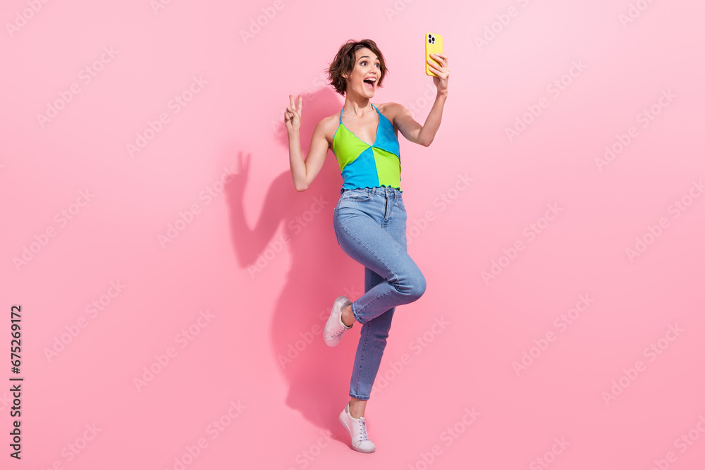 Full length illustration of hipster woman makes selfie cadre show v sign friendly greetings using phone isolated on pink color background