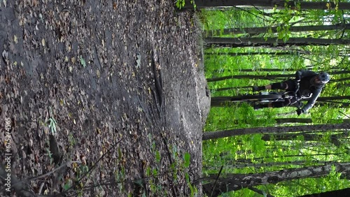 Vertical front shot of man jumping on electric bicycle in forest in slow motion photo