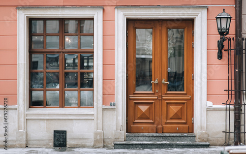 Old brown wooden window with rectangular frames for glass, a door and a house pink facade. Lviv, Ukraine.