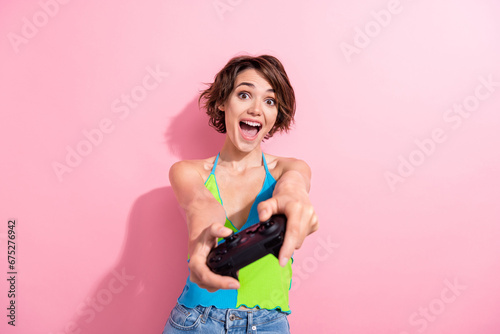 Photo of young girl holding wireless gamepad playing modern xbox one console wear bright trendy singlet isolated on pink color background