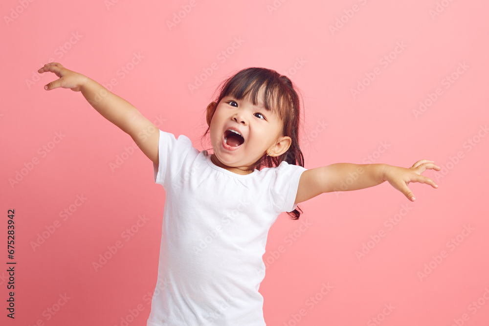 Joyful little Asian girl with her arms outstretched expresses fun and pleasure on isolated pink background. Happy child concept. Joyful little Asian girl with her arms outstretched expresses fun and pleasure on isolated pink background. Happy child concept.