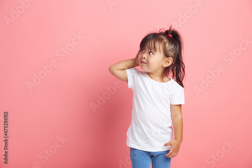 Curious little girl keeps hand near ear for eavesdropping likes gossip, wants to overhear secret information, wearing in white t shirt, tries to hear parents conversation. photo