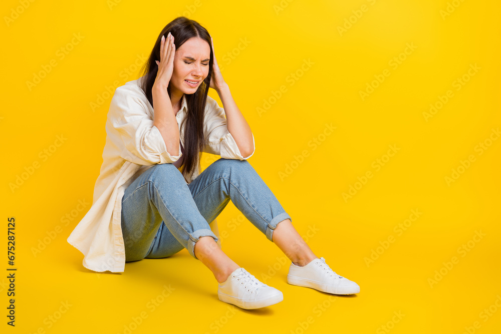 Full length profile photo of stressed unsatisfied person sit floor hands touch head empty space isolated on yellow color background Full length profile photo of stressed unsatisfied person sit floor hands touch head empty space isolated on yellow color background