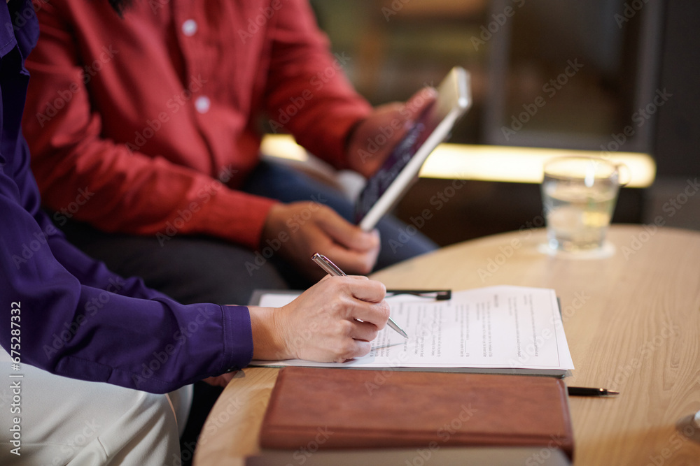 Hands of business partners reading contract before signing
