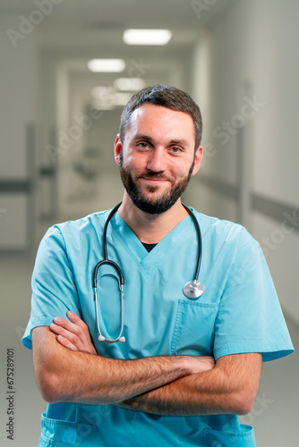 Portrait of a smiling doctor with a beard and a stethoscope around his neck in the corridor of spacious medical center